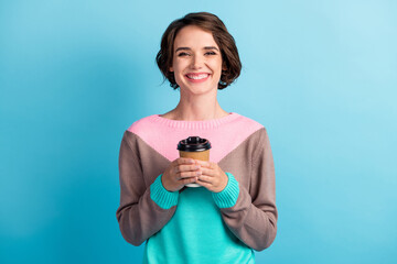 Photo portrait of happy smiling female student keeping paper cup of coffee smiling isolated on vibrant blue color background