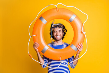 Photo of guy in scuba goggles hold life buoy near face wear striped blue shirt isolated over yellow...