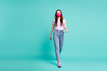 Photo of young charming girl walk towards you wear pink mask jeans violet t-shirt sneakers isolated turquoise color background