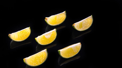 Slices and slices of lime lemon on a black background close up