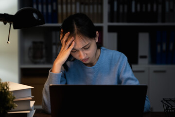 Asian business woman suffers from headache from working with computers for a long time.