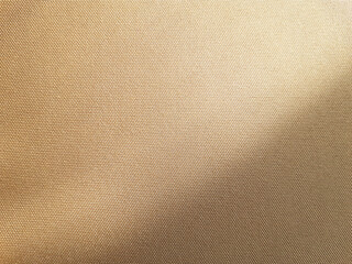 Horizontal plain background of beige yellow golden fabric with one slight smooth fold, creating a light wave