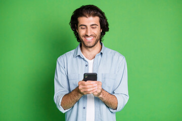 Photo of guy hold telephone look screen white shiny smile wear denim shirt isolated green color background