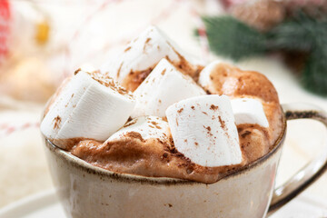 Hot cocoa or hot chocolate with marshmallows in a ceramic Cup surrounded by gingerbread, Christmas tree branches and ornaments on a brown wooden table. Christmas or new year's composition