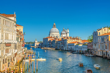Venice cityscape with Grand Canal waterway. Gondolas and boats docked and sailing Canal Grande. Santa Maria della Salute Roman Catholic church on Punta della Dogana. Veneto Region, Italy.