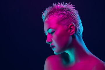 Sensual. Portrait of female fashion model in neon light on dark studio background. Beautiful caucasian woman with trendy make-up and well-kept skin. Vivid style, beauty concept. Close up. Copyspace
