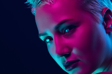Sensual. Portrait of female fashion model in neon light on dark studio background. Beautiful caucasian woman with trendy make-up and well-kept skin. Vivid style, beauty concept. Close up. Copyspace