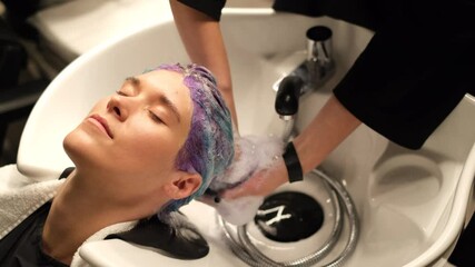 Hairdresser washes colorful purple blue womans hair in beauty salon      - Powered by Adobe