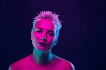 Dream. Portrait of female fashion model in neon light on dark studio background. Beautiful caucasian woman with trendy make-up and well-kept skin. Vivid style, beauty concept. Close up. Copyspace