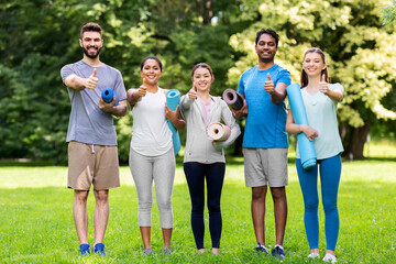 fitness, sport and healthy lifestyle concept - group of happy people with yoga mats showing thumbs...