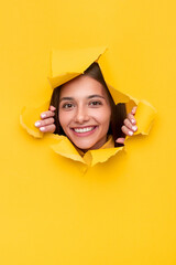 Young brunette tearing yellow paper