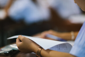 Students writing and reading exam answer sheets exercises in classroom of school with stress