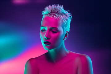 Shiny. Portrait of female fashion model in neon light on dark studio background. Beautiful caucasian woman with trendy make-up and well-kept skin. Vivid style, beauty concept. Close up. Copyspace