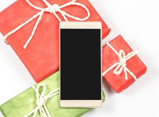  flat lay of blank screen mobile phone,on red and red  gift box on white background with copy space.Seasonal and holiday,  communication , online shopping concept.