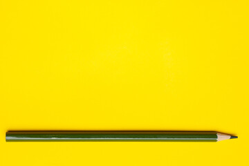 horizontal dark green sharp wooden pencil on a bright yellow background, isolated, copy space, mock up.