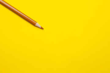 diagonal light brown sharp wooden pencil on a bright yellow background, isolated, copy space, mock up.