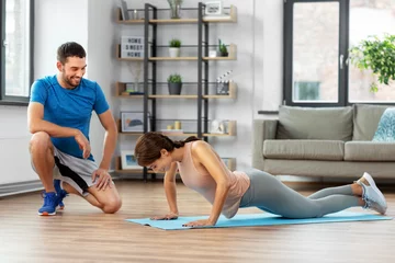 Gordijnen fitness, sport, training and lifestyle concept - happy smiling woman with personal trainer doing push-ups at home © Syda Productions