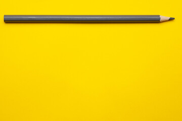 horizontal gray sharp wooden pencil on a bright yellow background, isolated, copy space, mock up.