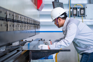 Asian technician worker wearing a safety suit and sheet Metal Bending in industrial factory, Safety first concept.
