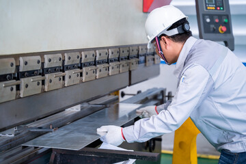 Asian technician worker wearing a safety suit and sheet Metal Bending in industrial factory, Safety first concept.