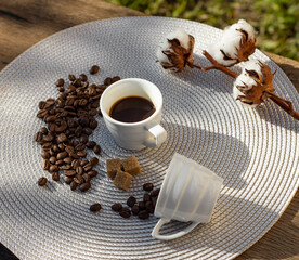 Still life with coffee cup, beans, brown sugar and cotton flower in the sun