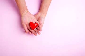 Two hands are holding a heart on a pink background. Flatley style