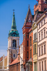 Fototapeta na wymiar Church of the Holy Spirit surrounded by buildings under the sunlight and a blue sky in Torun, Poland