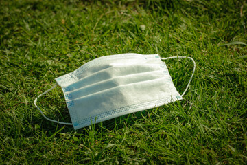 Medical face mask in the grass. Social distancing to prevent spread of COVID-19 coronavirus in the...