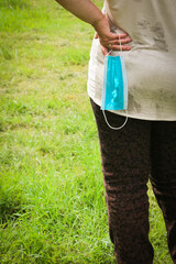 An elderly plump Woman walking through the Park with a protective Mask in her Hand. Coronavirus Quarantine stop.