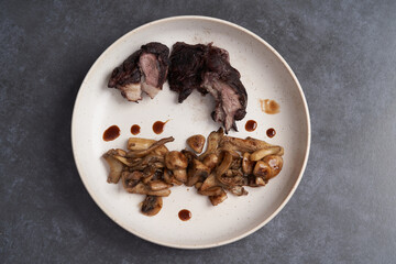 Baked lamb chops and mushrooms on a white plate.