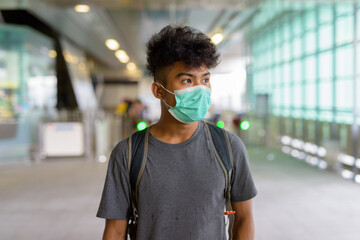 Young Asian tourist man as backpacker with mask thinking at the sky train station