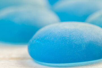 Blue bright glass glossy stones with white wooden background macro