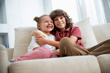Obraz premium Girl with brother is hugging on sofa