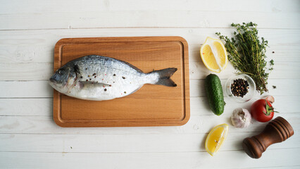 Raw fish cooking and ingredients. Dorado, lemon, herbs and spices. Top view on stone table