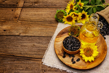 Sunflower oil in glass cruet with flower head and seeds in wooden bowl