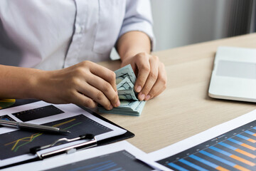 Fototapeta premium A woman counting money on her desk with her hand. Business concept.