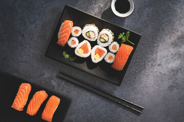 Japanese sushi food. Maki and  rolls with spicy tuna, salmon, tofy and  avocado. Top view of assorted sushi, uramaki, hosomaki and nigiri on the stone dark background