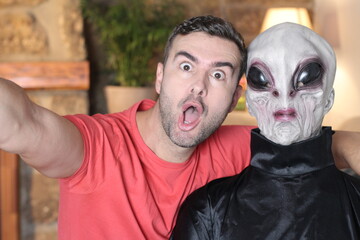 Surprised man taking a selfie with an alien 
