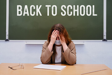 Crying teacher sits in a school class with the text 