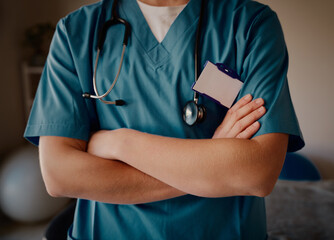 Closeup of young female doctor with folded arms and stethoscope standing