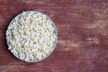 Popcorn in white ceramic bowl on red background. Top view, flat lay. Copy space