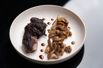 Baked lamb chops and mushrooms on a white plate.
