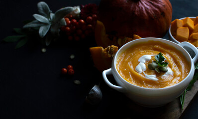 Vegetarian autumn pumpkin cream soup with seeds in white bowls on a dark background.The concept of healthy and vegetarian food.