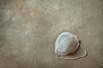 Fototapeta na wymiar Used construction mask, lying on the gray concrete floor.