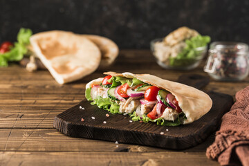 National Greek fast food pita with chicken and fresh vegetables on a wooden Board