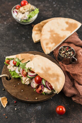 National Greek fast food pita with chicken and fresh vegetables on a wooden Board dark background