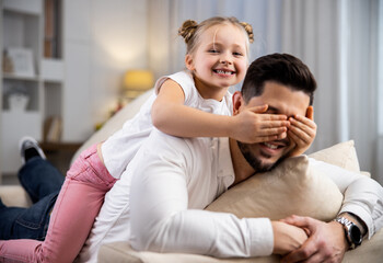 Daughter covering her dad's eyes with a palm