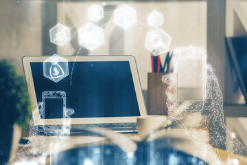 Computer on desktop in office with technology theme hologram. Double exposure. Tech concept.