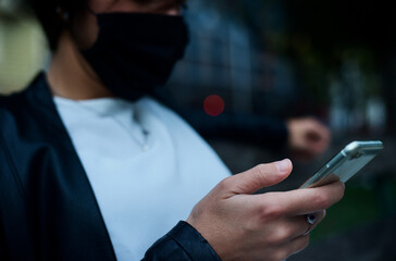 detail of woman hand with telephone. on the face wearing mask in time of corona virus