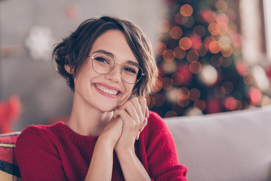 Photo of cute young lady hold hands beaming white smile look camera wear eyewear red sweater indoors